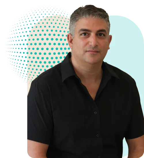 Eye Care Doctor Portrait of a man in a black shirt, with a teal dotted circular backdrop and black background behind him.